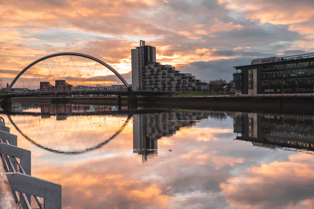 Stunning view of Glasgow's Clyde Arc reflecting in the River Clyde at sunset with modern architecture.