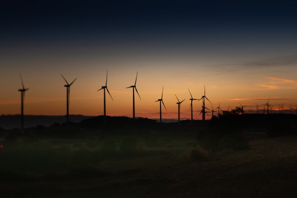 Silhouettes of wind turbines against a vibrant sunset in Lleida, Spain.